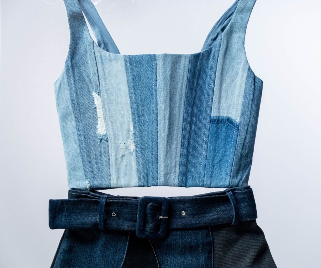 Close-up of a denim dress with a belt, highlighting fashion elements.