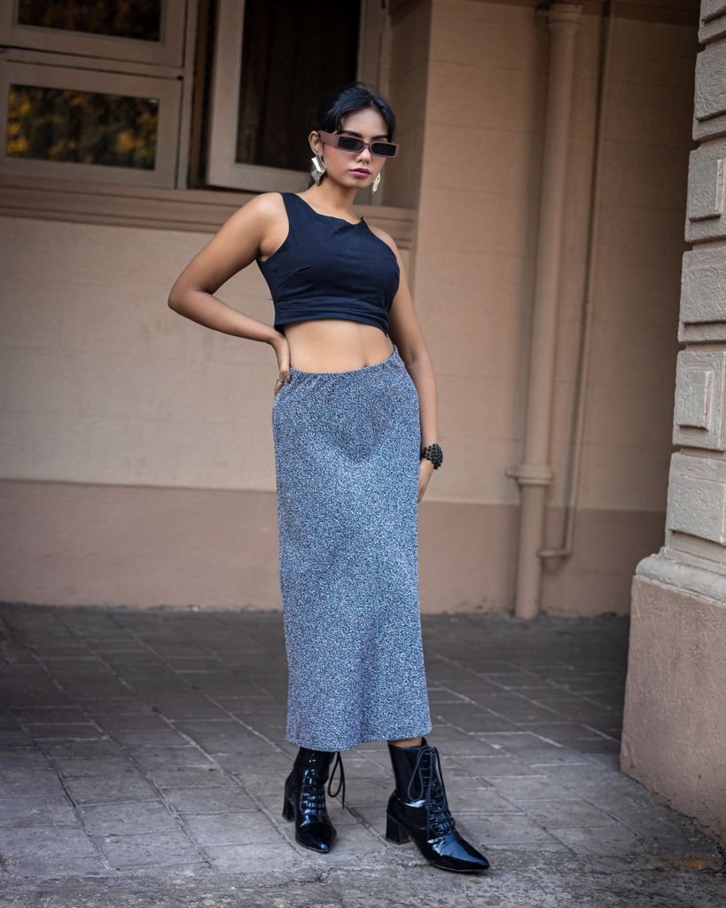Confident young woman in trendy streetwear poses stylishly in an urban environment.